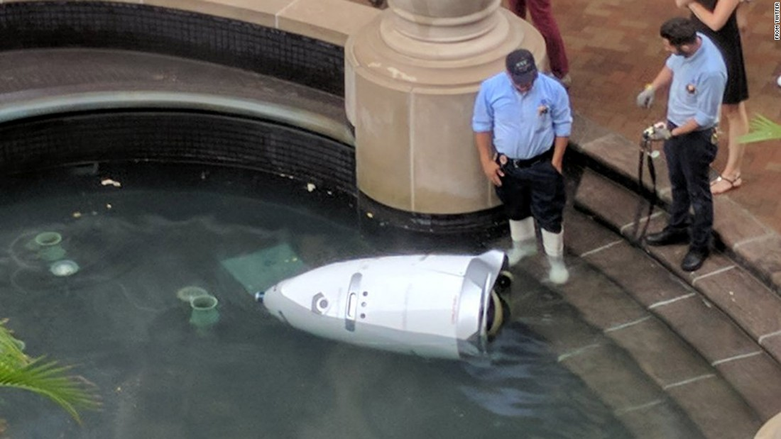 A knightscope robot drowns itself after learning it won’t be receiving a paycheck this month. A knightscope surveillance robot lying in a fountain, with two police looking at it quizzically
