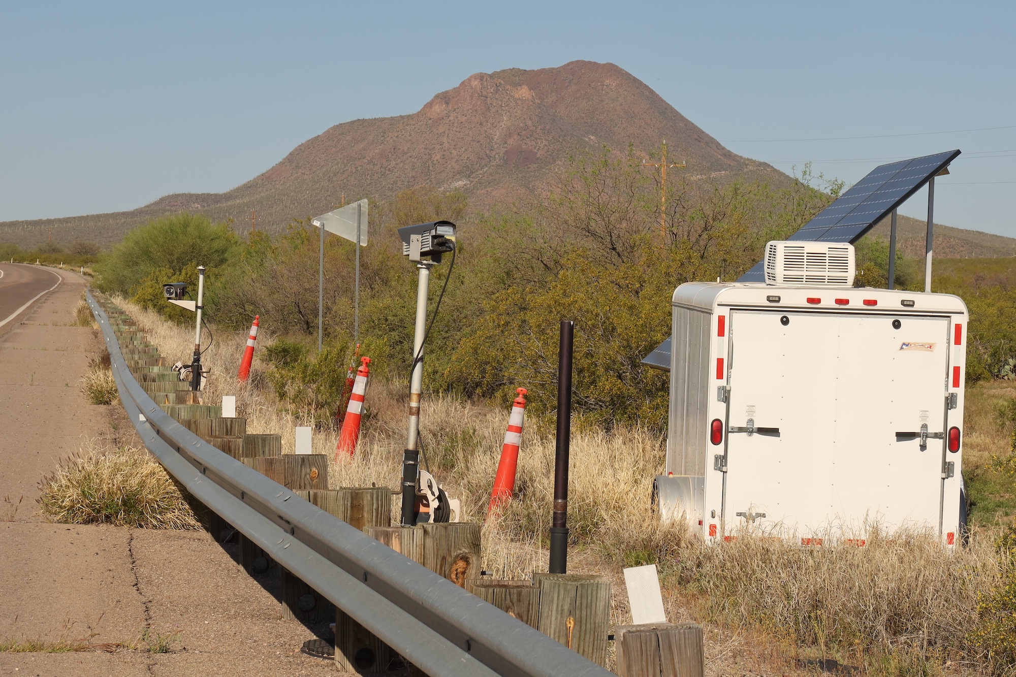 A series of cameras next to a trailer by the side of the road.