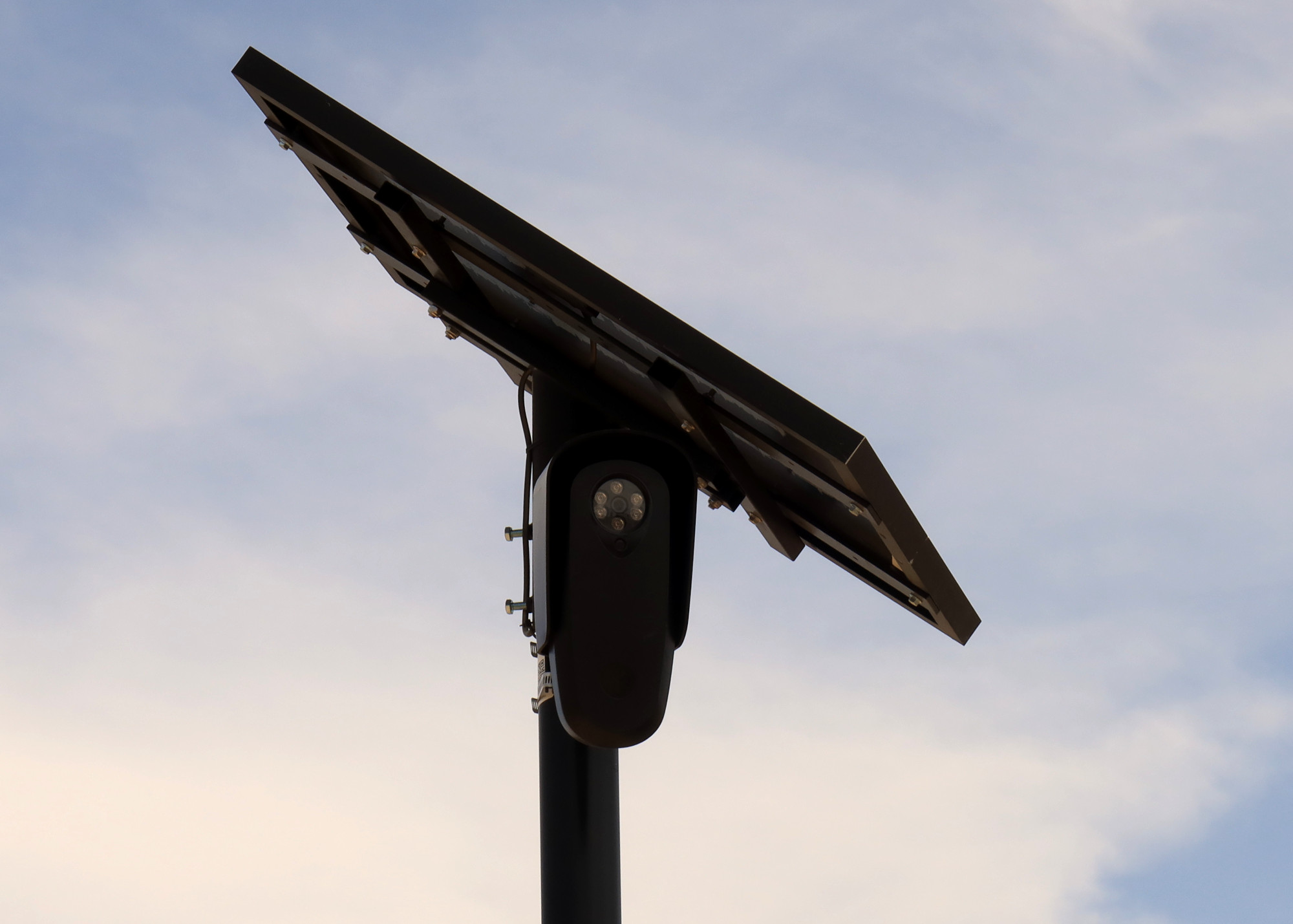 A black Flock Safety camera with a small solar panel