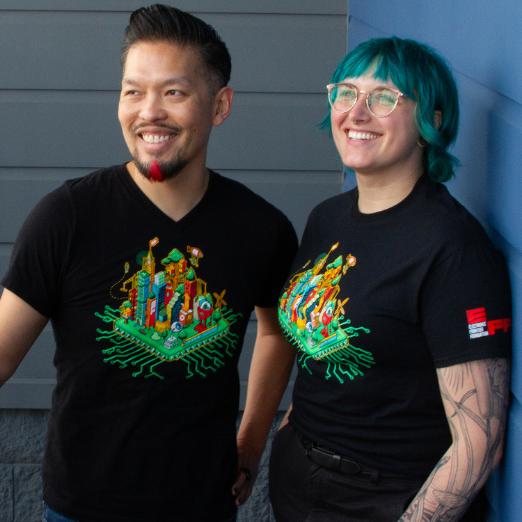 Two people wearing black t-shirt with a green EFF 35th Anniversary digital cityscape on the front. Two people wearing black t-shirt with a green EFF 35th Anniversary digital cityscape on the front.